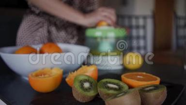 成熟的切片猕猴桃和橘子放在一张黑桌子上。 在背景中做新鲜的果汁是模糊的。 关门